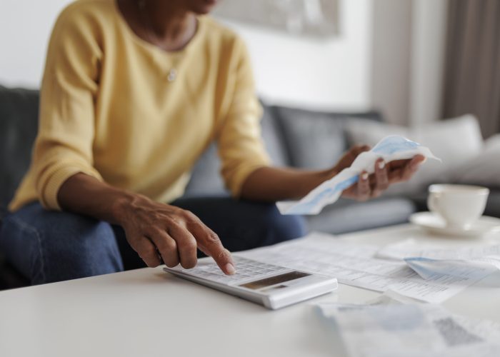 Close up of a mid adult woman checking her energy bills at home, sitting in her living room. She has a worried expression